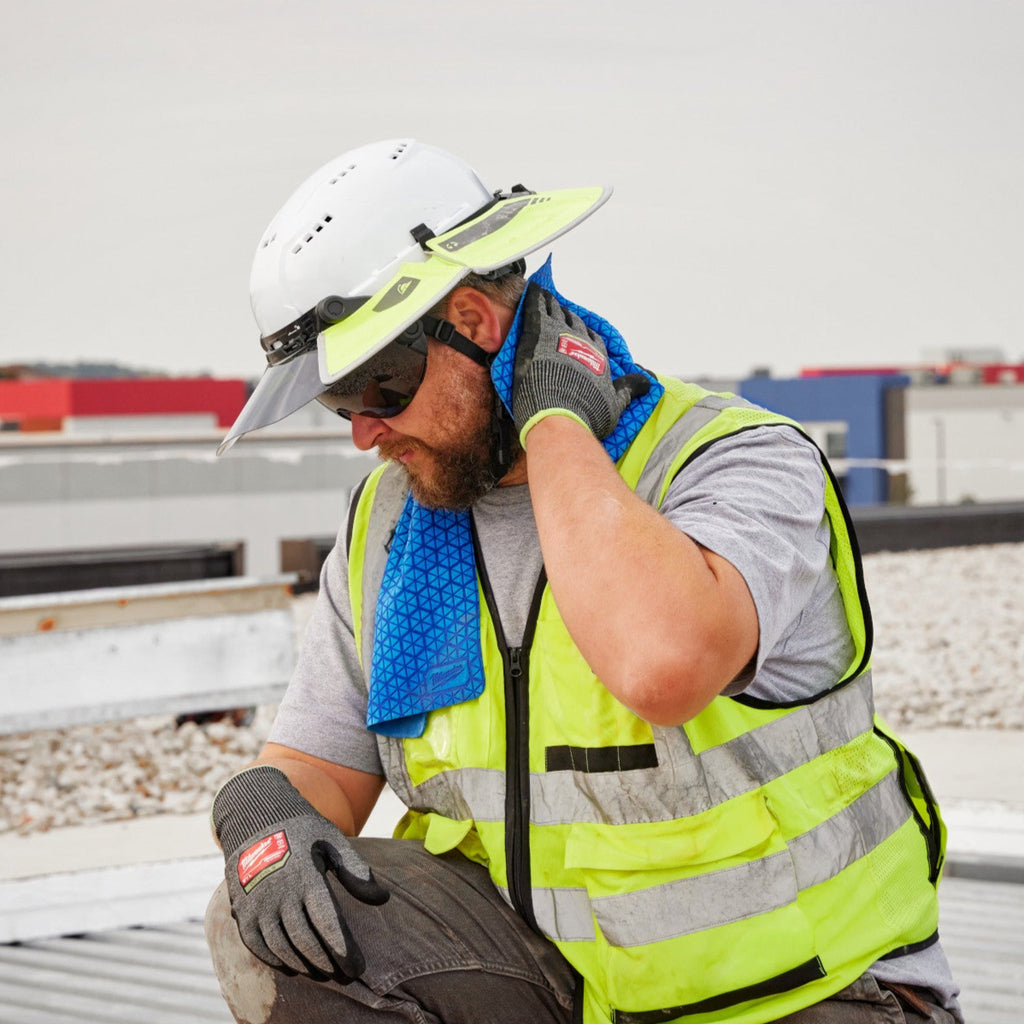 Worker on a construction site wearing safety gear and a high-visibility vest.